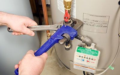 deux mains manipulant un outil servant à régler un chauffe-eau