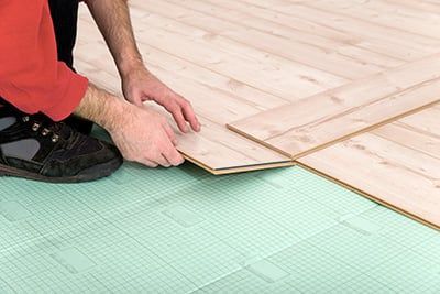 mains posant du parquet sur de l'isolant