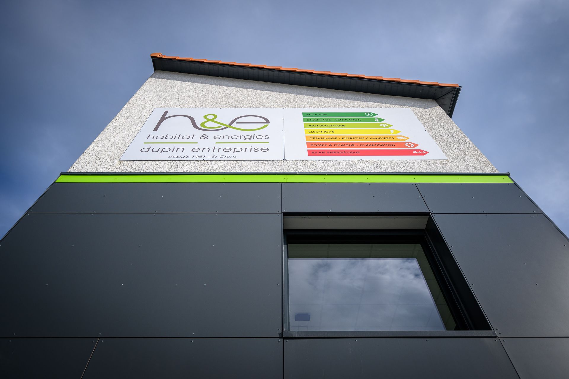Vue en contre-plongée d'un bâtiment moderne avec une bande verte. Logo et tableau d'efficacité énergétique inclus.