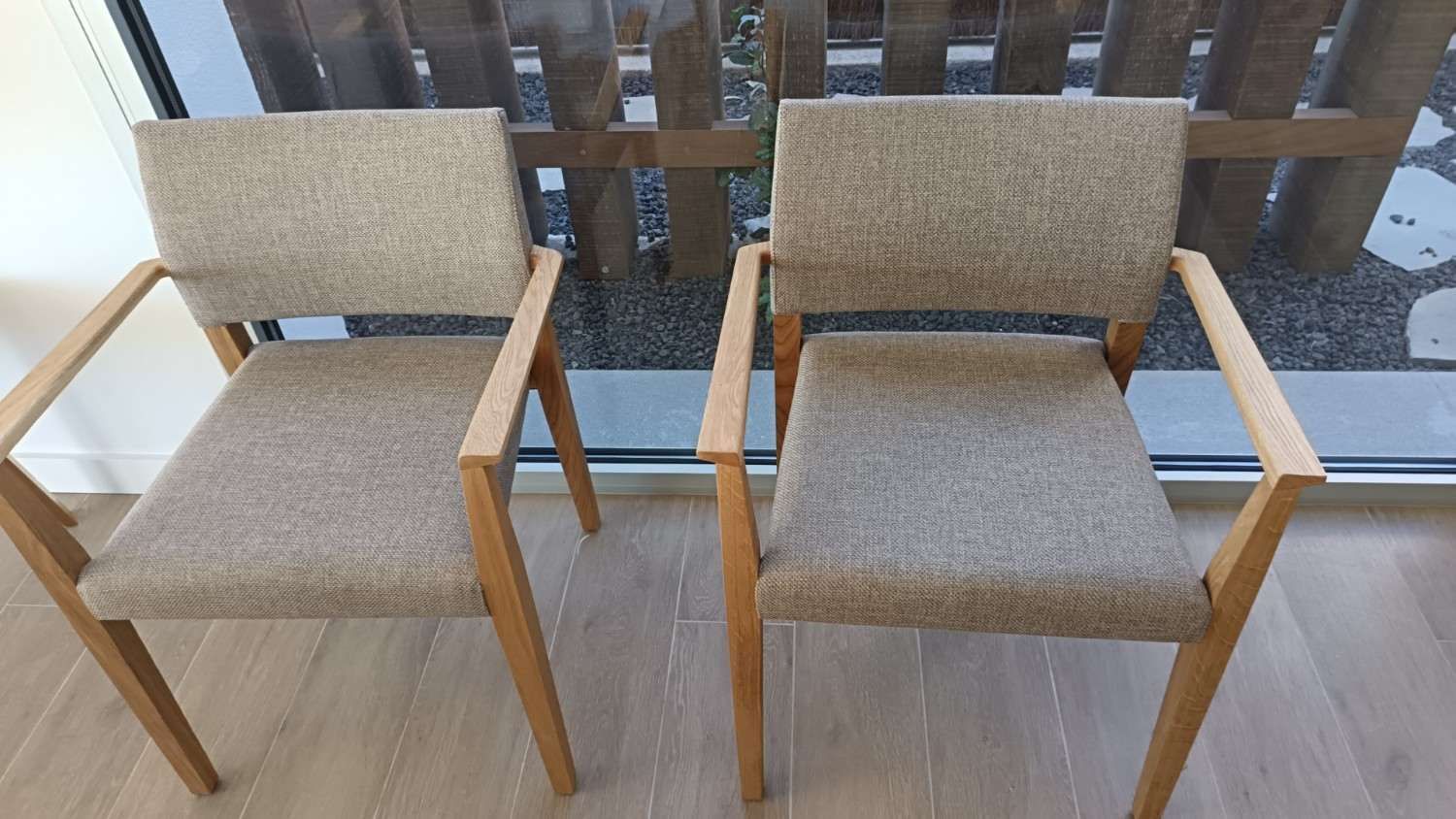 Dos sillas de madera tapizadas en color beige sobre un suelo de baldosas, vistas desde arriba.