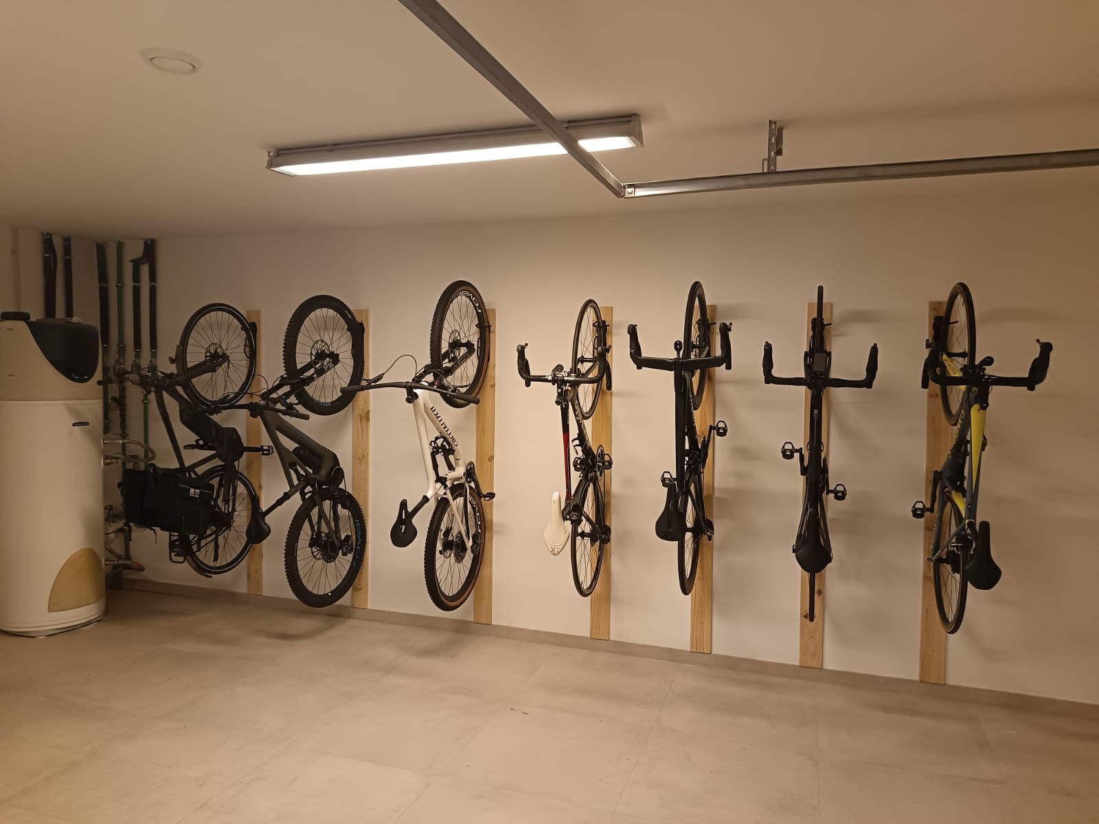 Zona de almacenamiento interior para bicicletas con varias bicicletas montadas en soportes de pared bajo luces fluorescentes.