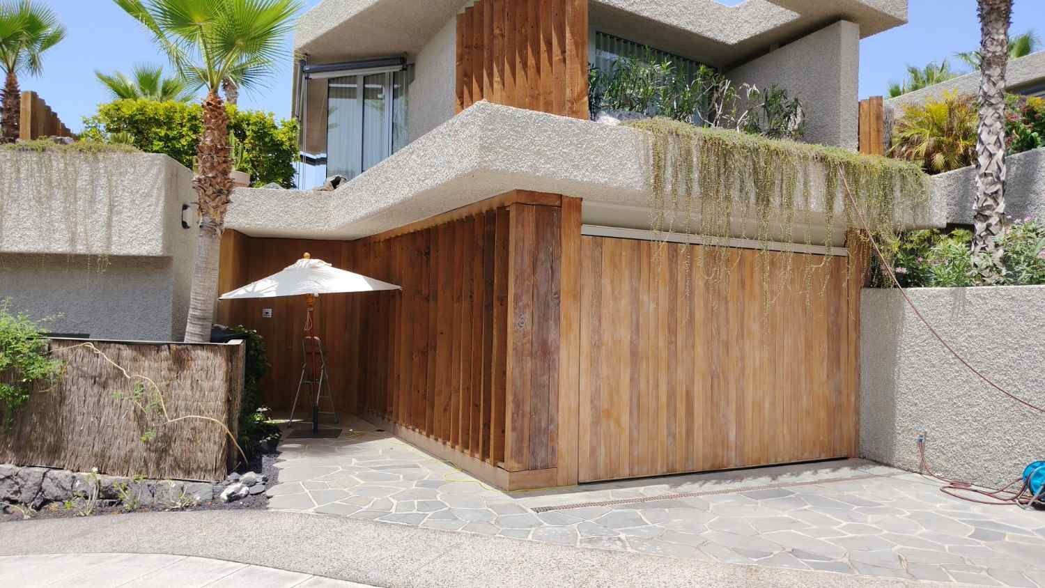 Casa moderna de dos plantas con exterior de madera y hormigón, balcón y entrada con patio.