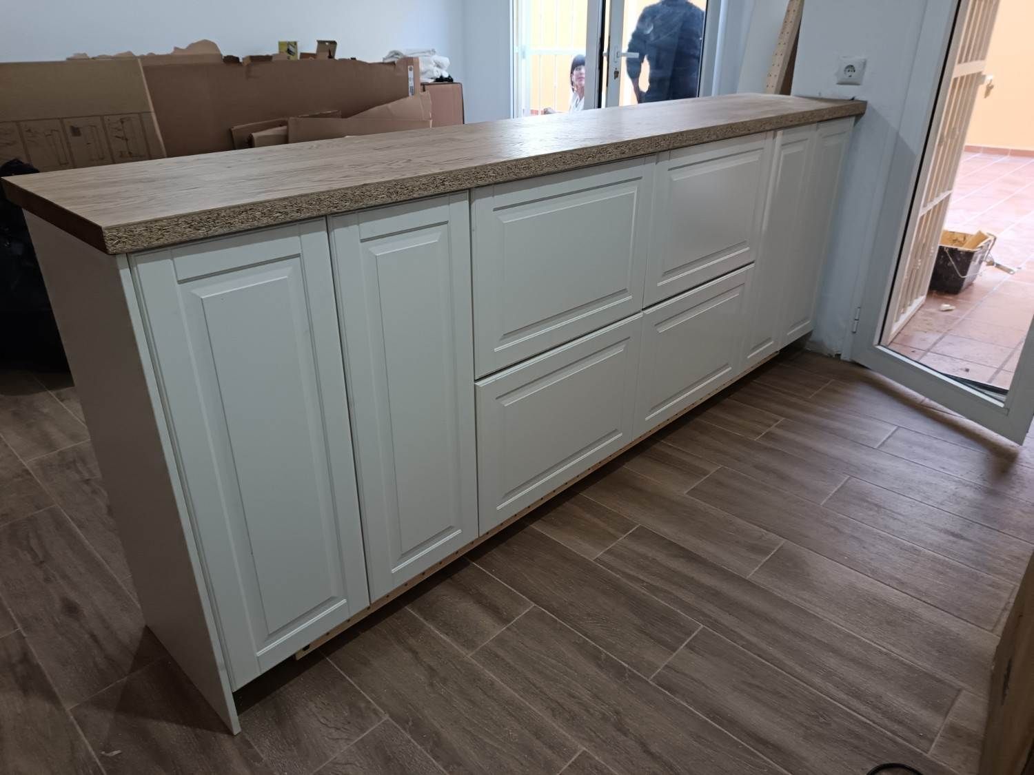 Mueble de isla de cocina blanco con encimera moteada en una habitación con suelo de madera.