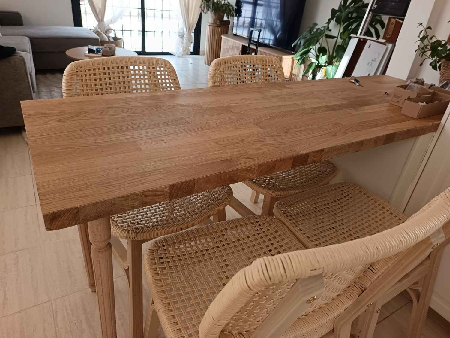 Mesa de comedor de madera con sillas de mimbre en una luminosa sala de estar.