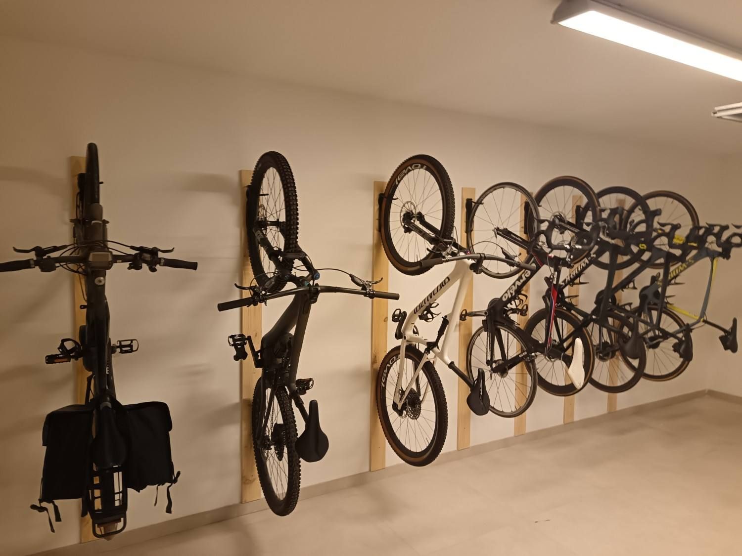 Bicicletas montadas en soportes de pared en un garaje o trastero interior de color beige.