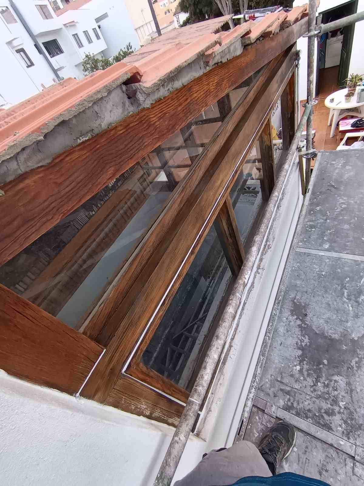 Vista inclinada de una claraboya en la azotea con marco de madera marrón junto a una terraza de hormigón.