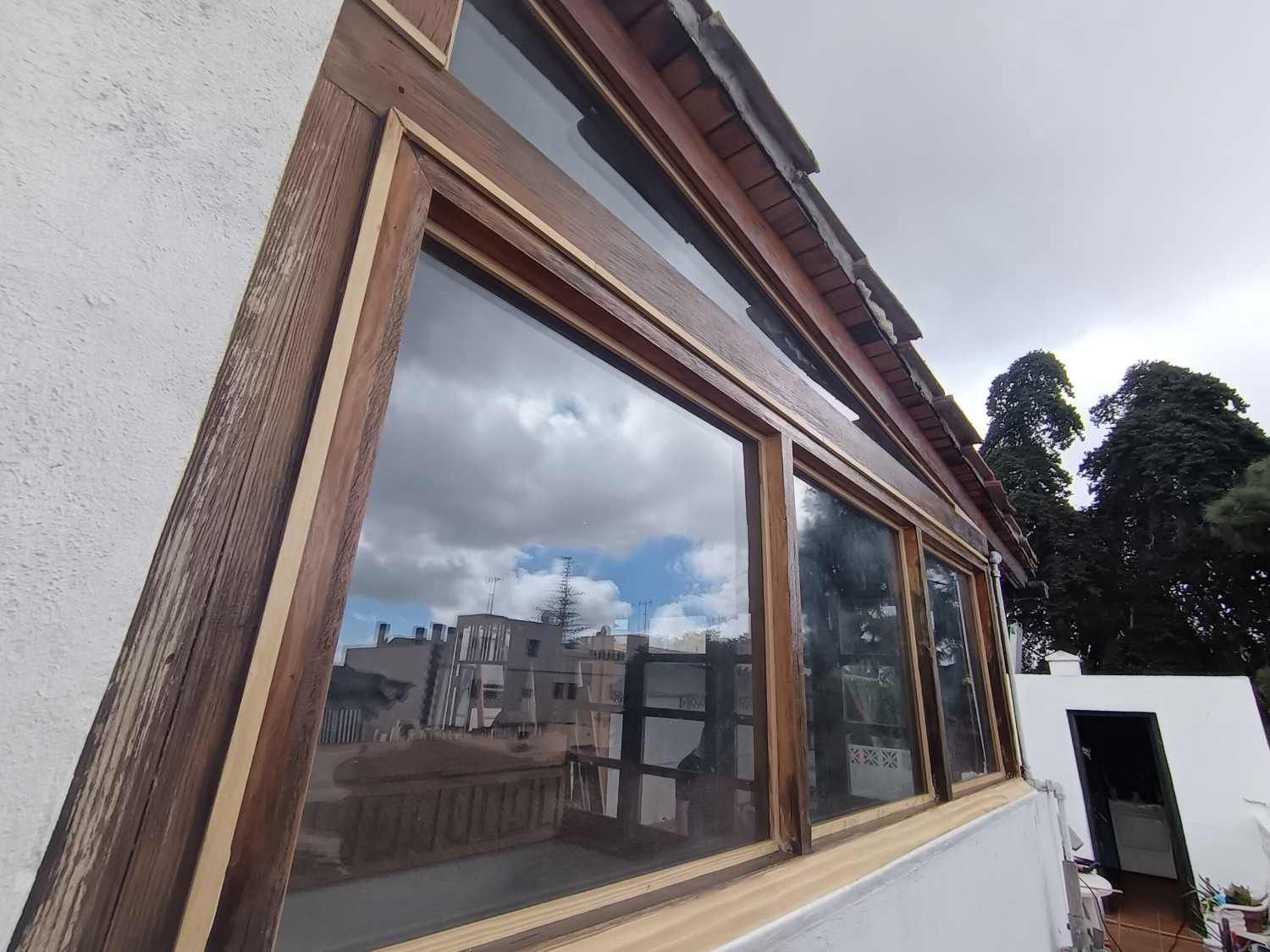 Ventanas de edificios con marcos de madera que reflejan el cielo nublado y los edificios cercanos.