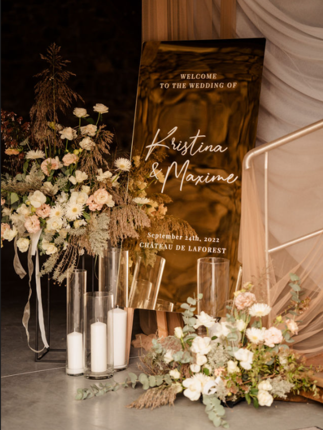 Panneau de bienvenue pour Kristina Maxine entouré de compositions florales blanches et roses et de bougies