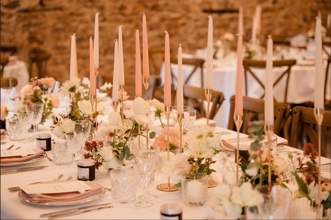 Élégante table de banquet dressée avec des fleurs blanches, des bougies et des chaises dorées dans une salle intérieure chaleureuse