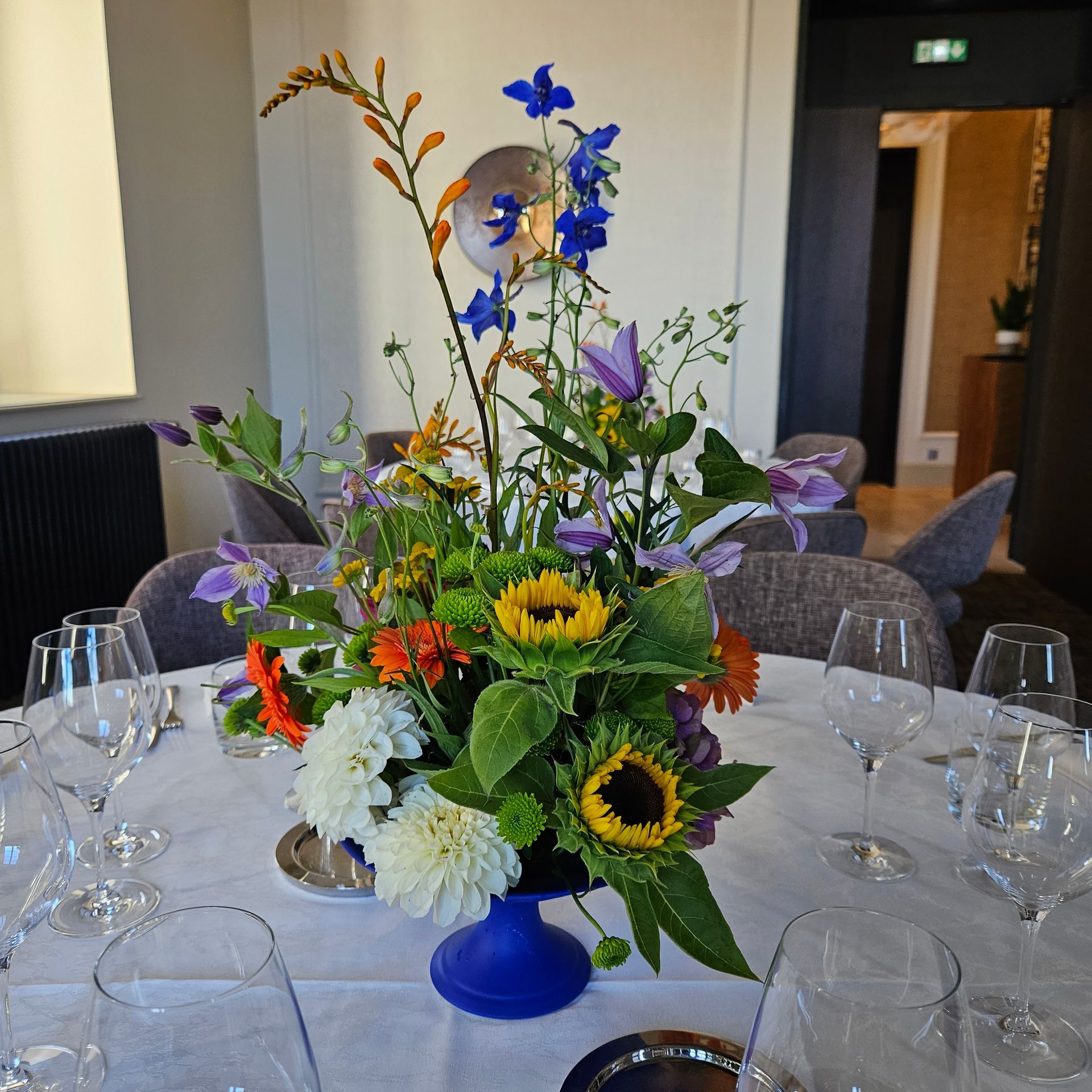 Un centre de table floral coloré avec des tournesols et des fleurs bleues sur une table de banquet dans une salle à manger