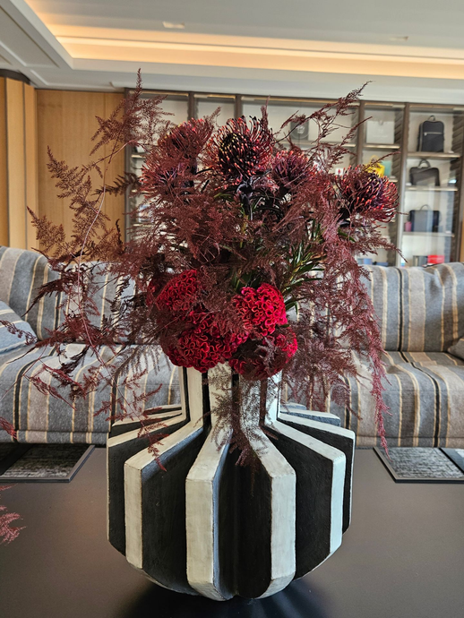 Composition florale rouge dans un vase noir et blanc sur une table de salon