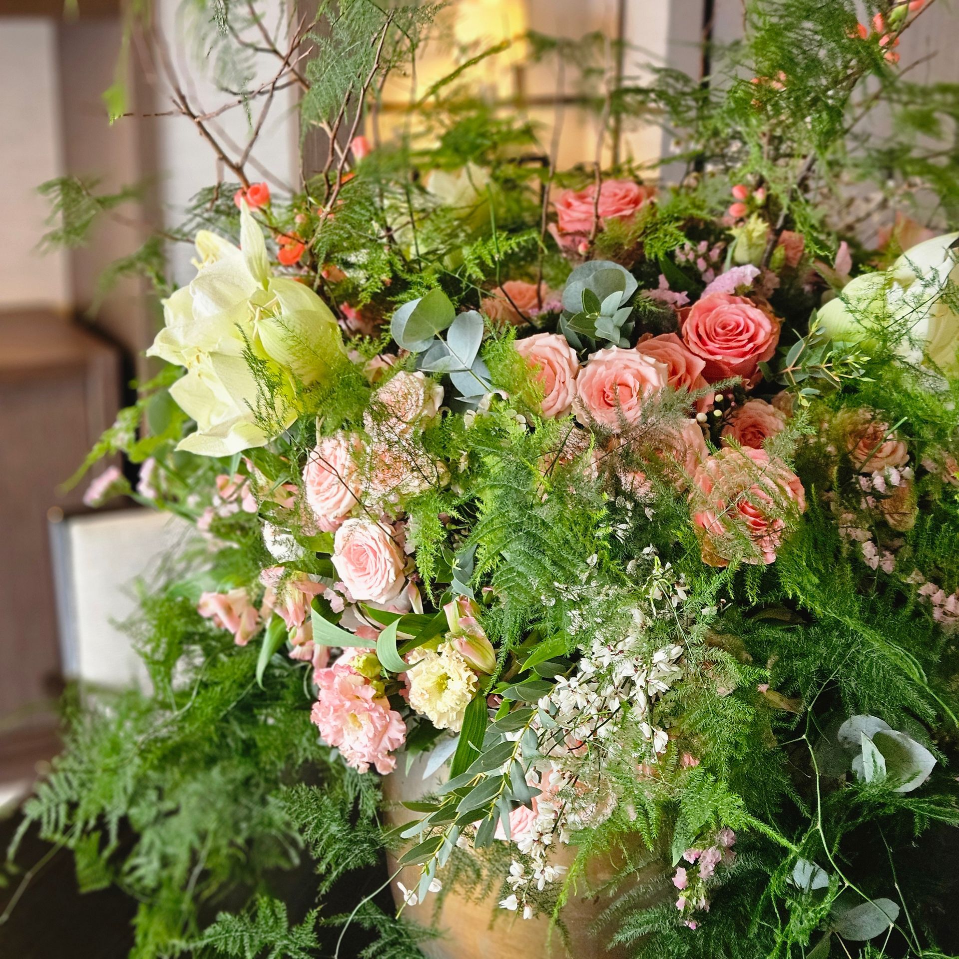Une composition florale luxuriante avec des fleurs roses, blanches et vertes et de la verdure dans un cadre décoratif