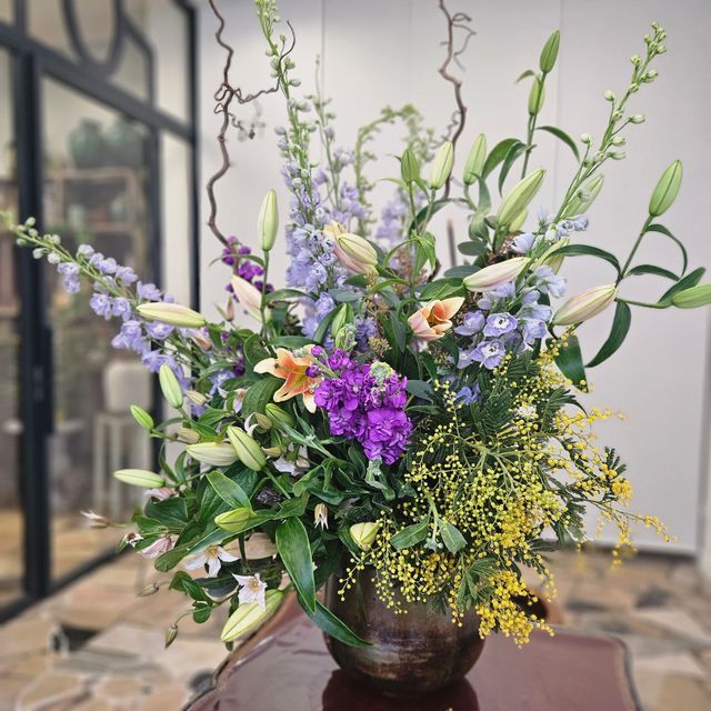 Bouquet de fleurs sauvages mélangées avec des fleurs violettes, jaunes, blanches et orange dans un vase sombre sur une table