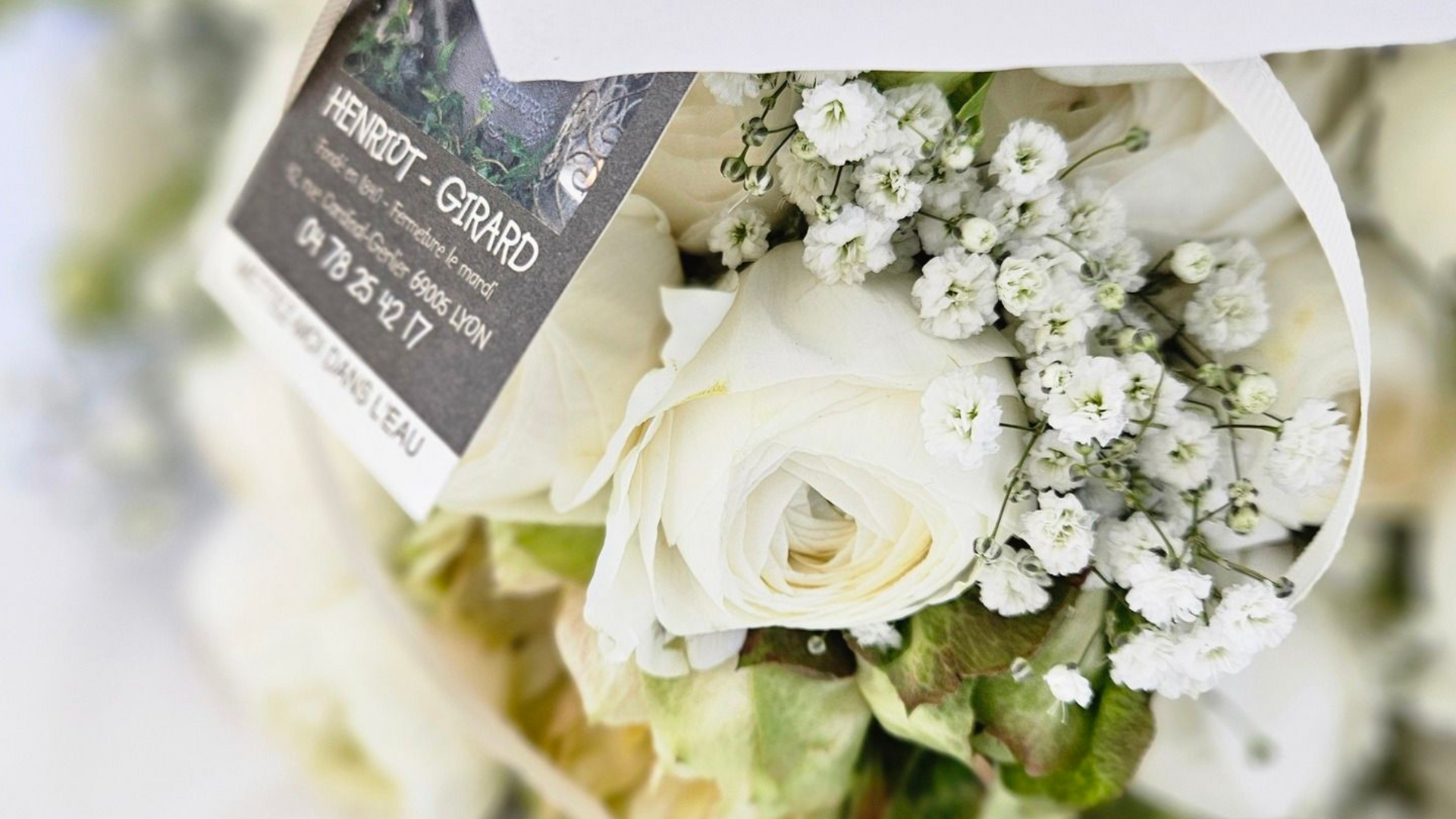 Bouquet de roses blanches avec du gypsophile et une étiquette en carton foncé au flou artistique