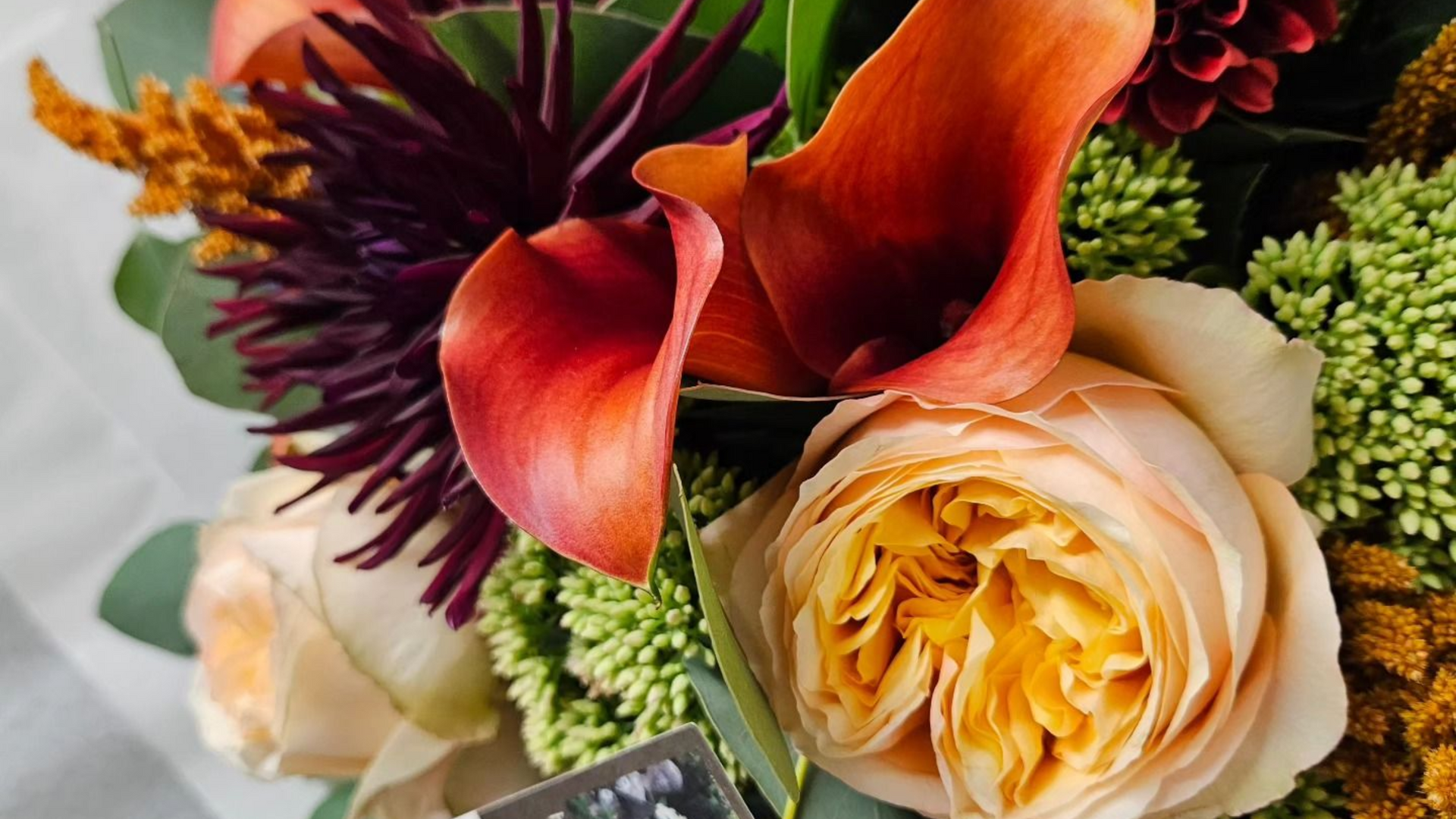 Bouquet de fleurs orange, crème et violet foncé avec des fleurs de remplissage vertes texturées