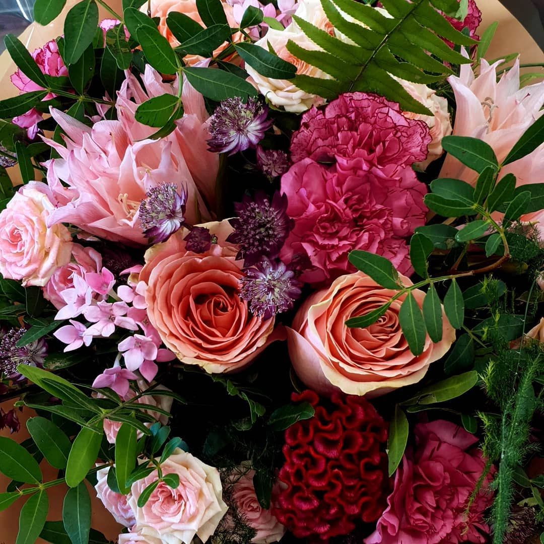 Un bouquet luxuriant composé de fleurs roses et rouges assorties et de feuillage vert.