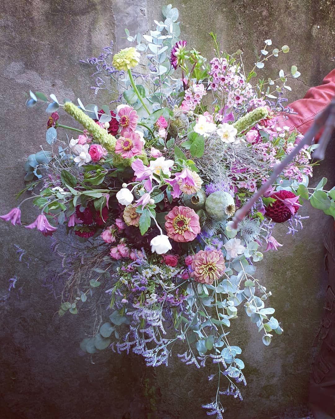 Bouquet de fleurs sauvages aux teintes pastel, avec des fleurs roses, blanches, jaunes et bleues sur un fond sombre texturé.