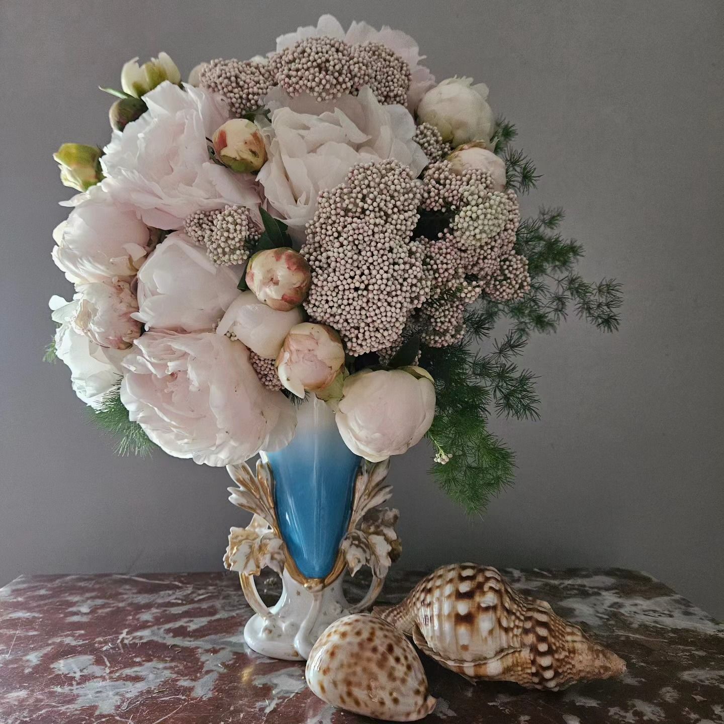 Bouquet de fleurs pastel dans un vase bleu avec des coquillages sur une table