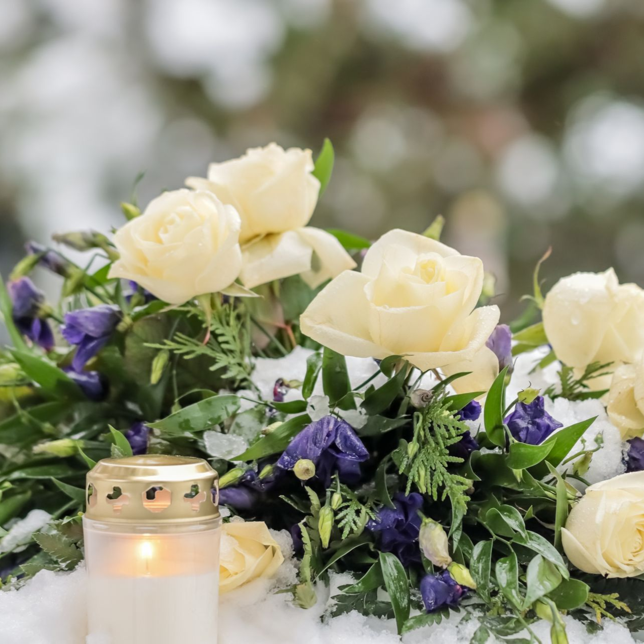 Des roses blanches et des fleurs violettes avec une bougie allumée sur une table