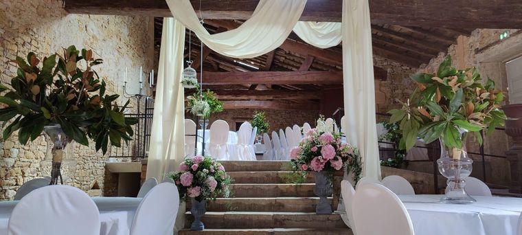 Autel de mariage décoré de draperies blanches, de compositions florales et d'escaliers dans un lieu intérieur rustique