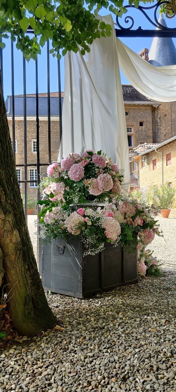 Composition florale rose et blanche sur un support sombre, à côté d'un drapé blanc à l'extérieur