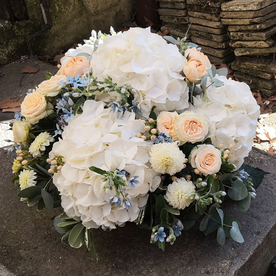 Composition florale blanche et crème avec des roses et des hortensias dans un cadre de jardin