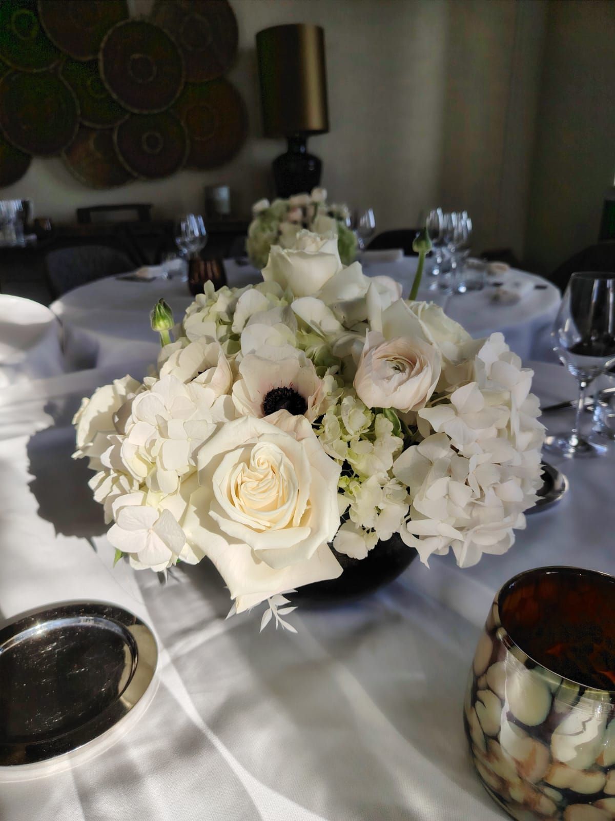 Centre de table floral blanc avec bougies et verrerie dans une ambiance tamisée