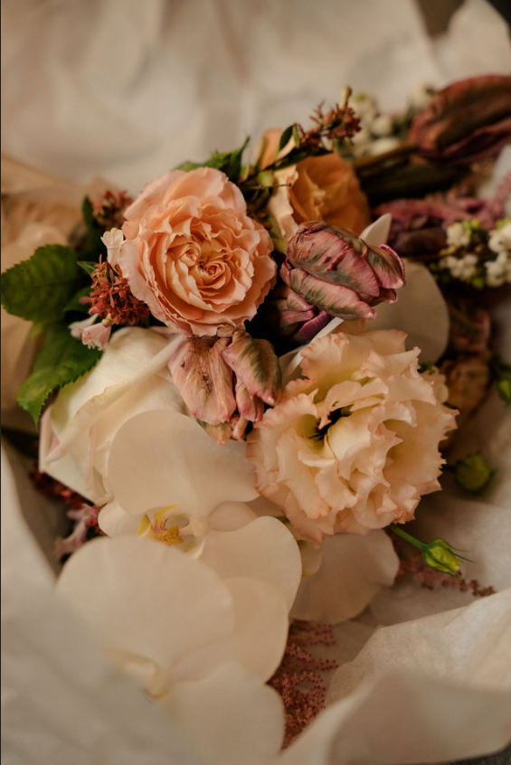 Bouquet pastel de roses et d'hortensias dans des tons rose tendre, crème et blanc, emballé dans du papier beige
