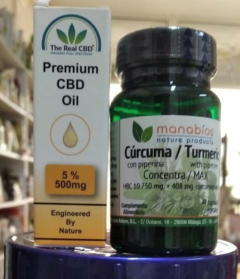 Una botella de aceite de CBD de primera calidad junto a una botella de cúrcuma.