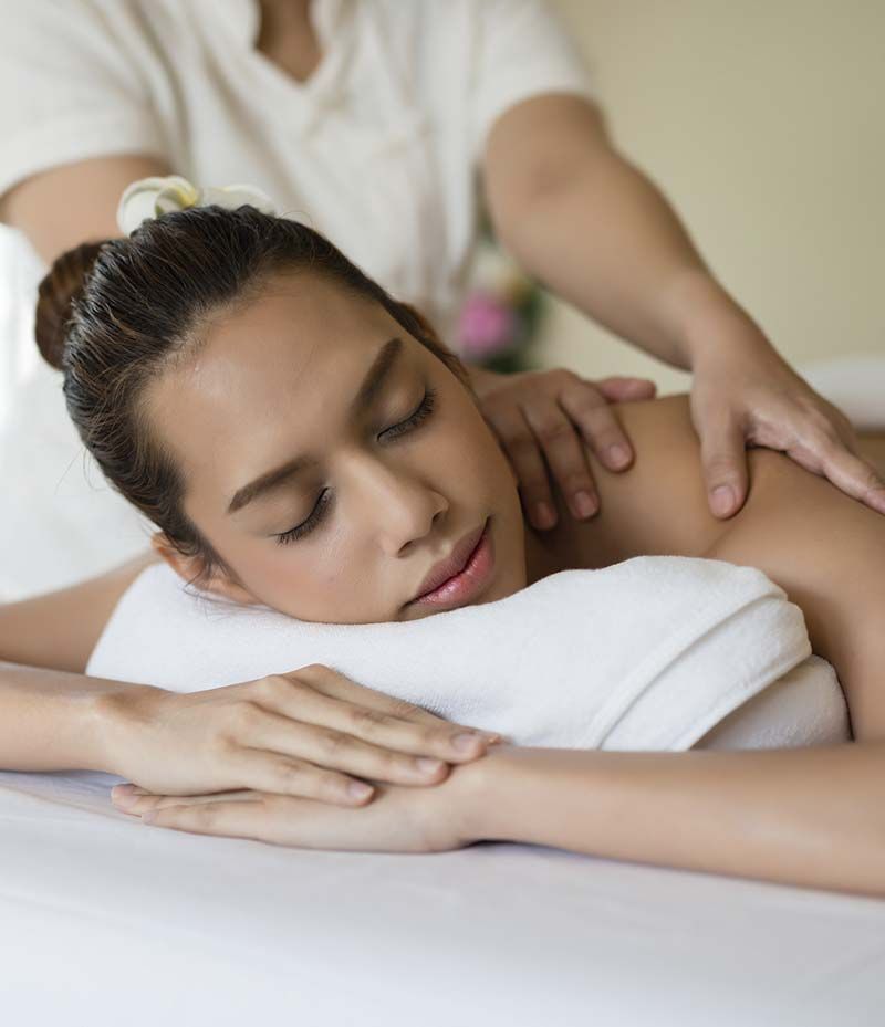 Una mujer está acostada en una cama recibiendo un masaje.