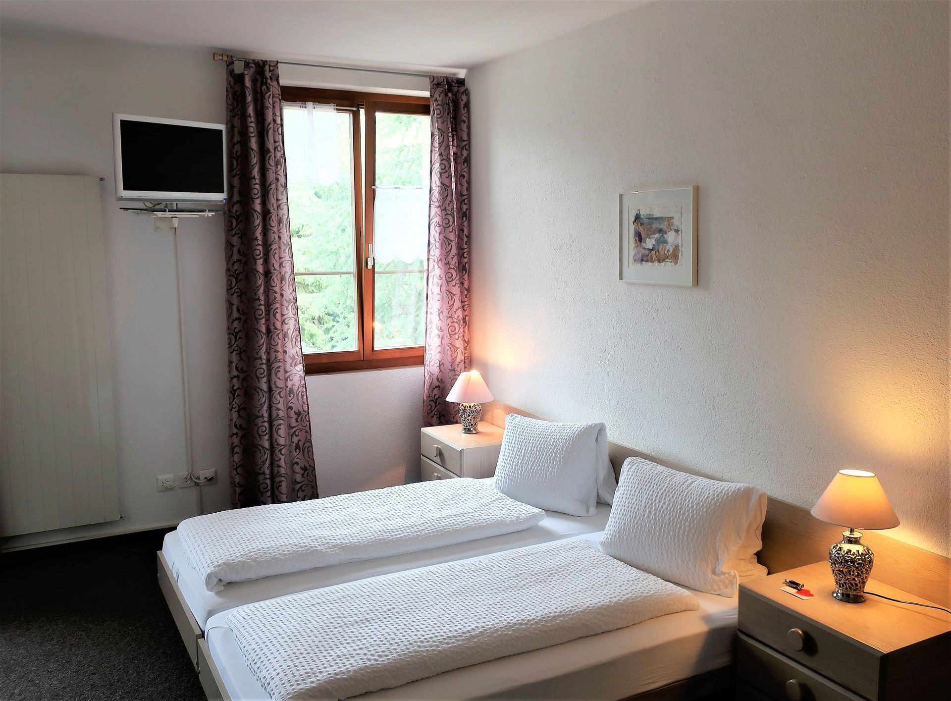 Ein Schlafzimmer mit zwei Betten und einem Fernseher an der Wand