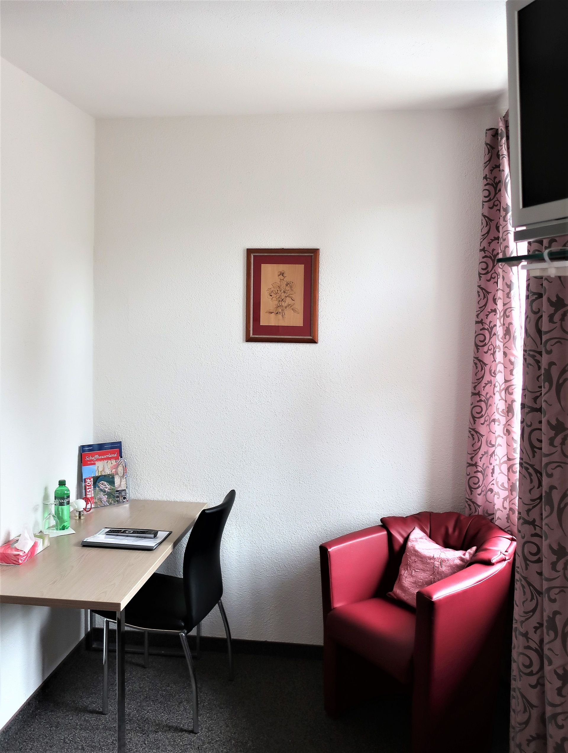 Ein kleines Zimmer mit einem roten Stuhl und einem Schreibtisch