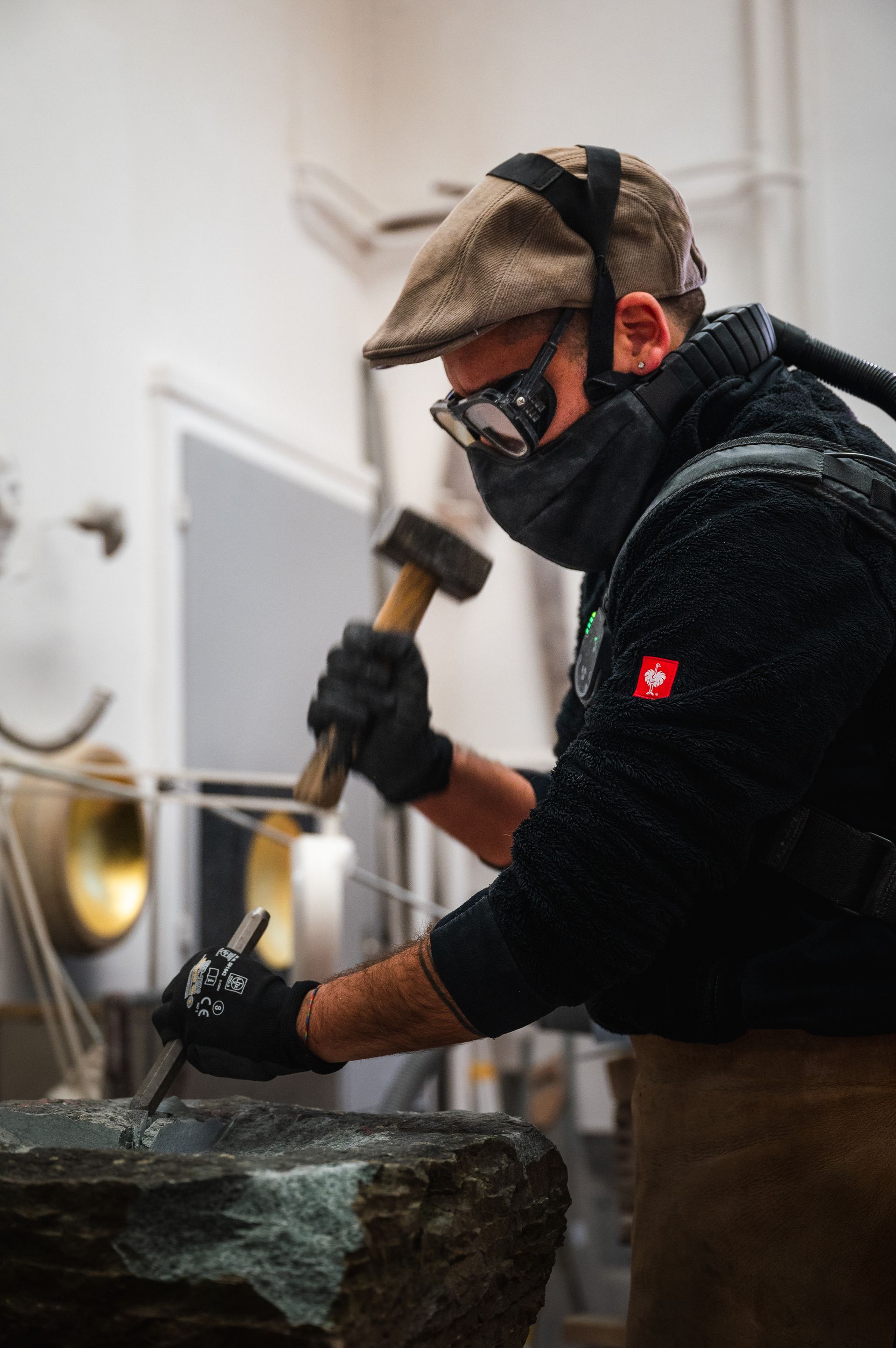 Ein Arbeiter schleift eine weisse Tischplatte in einer hellen Werkstatt mit grossen Fenstern.