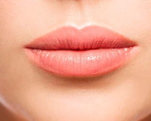 Un primer plano de los labios de una mujer con lápiz labial rosa.