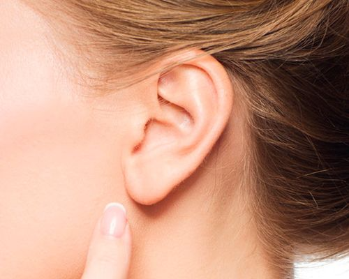 Un primer plano de la oreja de una mujer con su dedo sobre ella.