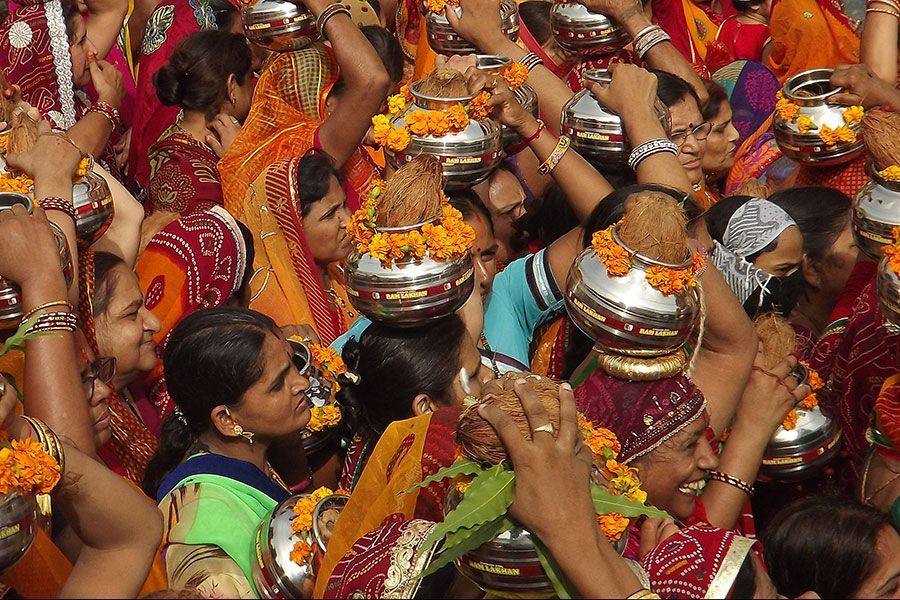 Una multitud de personas sostiene cuencos sobre sus cabezas.