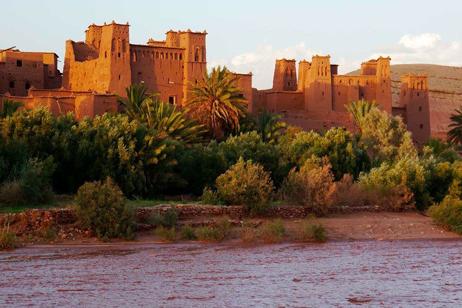 Un castillo está rodeado de árboles y un cuerpo de agua.