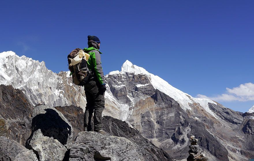 Una persona con una mochila está parada en la cima de una montaña.