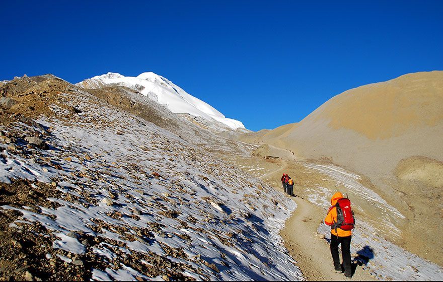 Un grupo de personas está caminando por una montaña nevada.