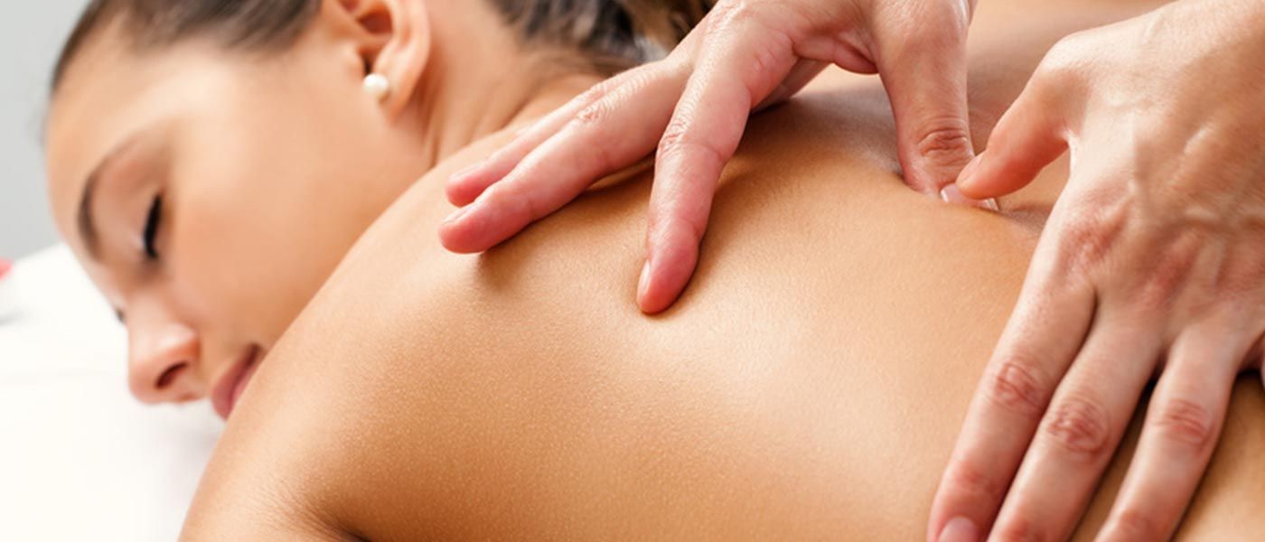 Entspannte Frau auf einer Massageliege, die massiert wird