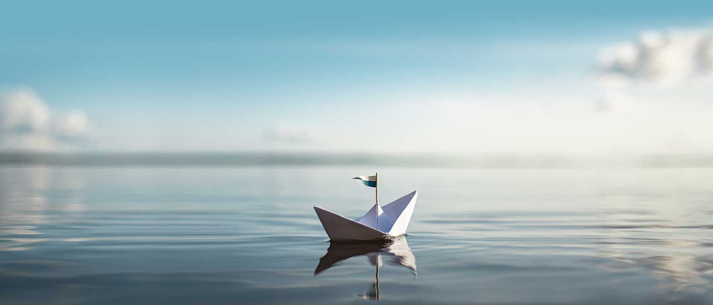 Ein Papierboot schwimmt auf einer Wasserfläche.