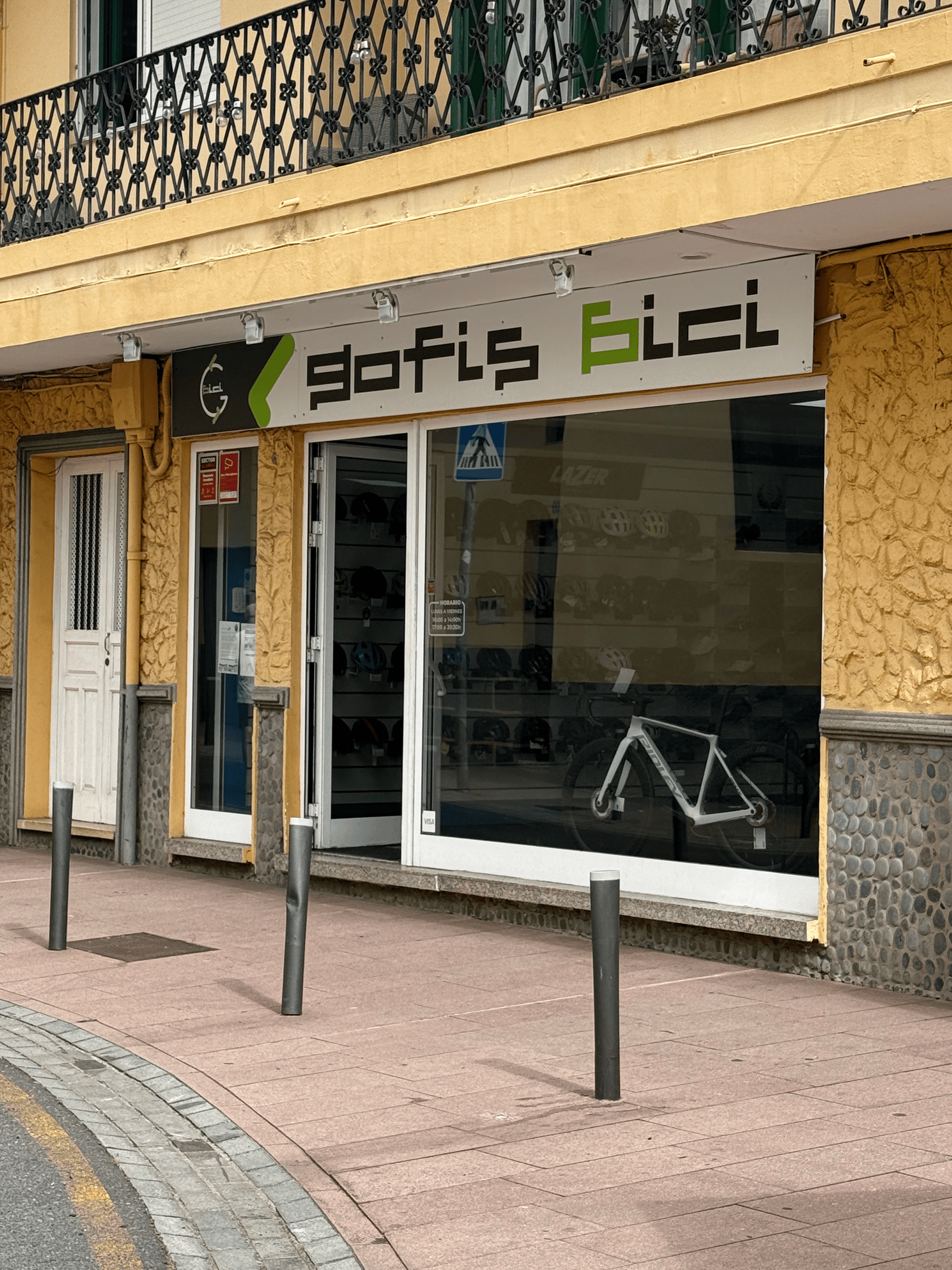 Local comercial con ventanas de cristal y letrero que dice “ofis bici” en la acera.