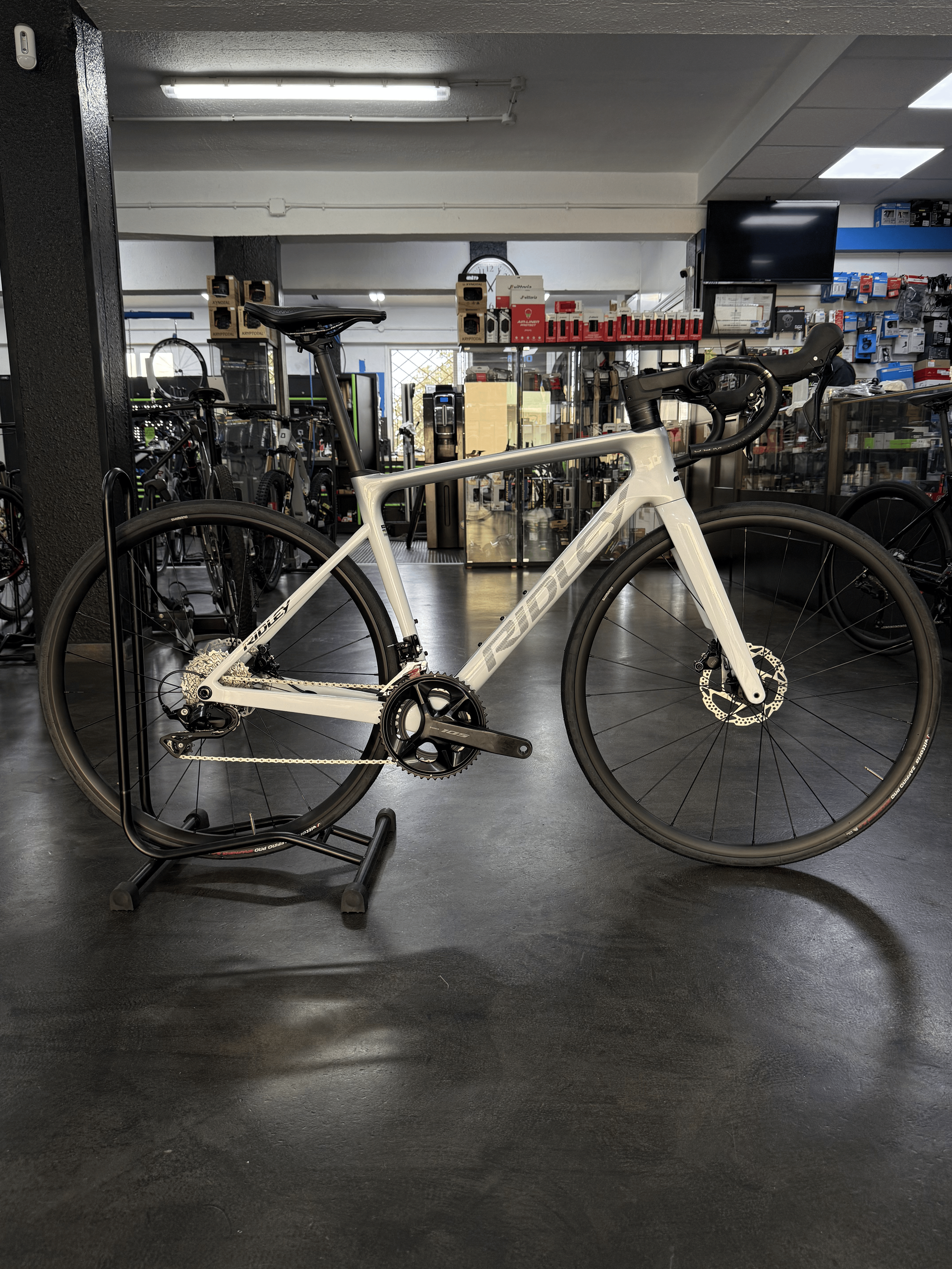 Bicicleta de carretera blanca sobre un soporte de reparación en el taller de una tienda de bicicletas.