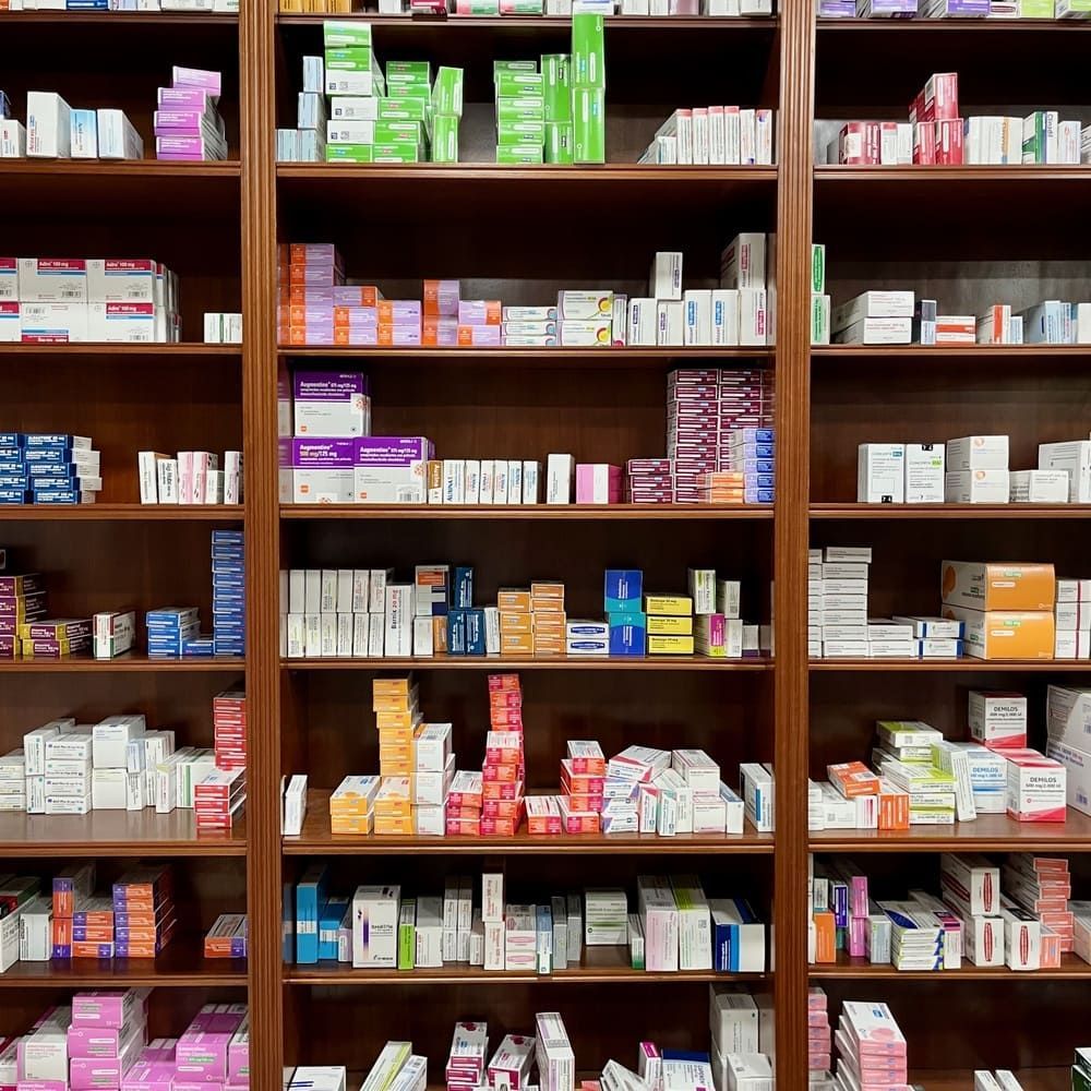 Una farmacéutica está de pie en una farmacia con los brazos cruzados.