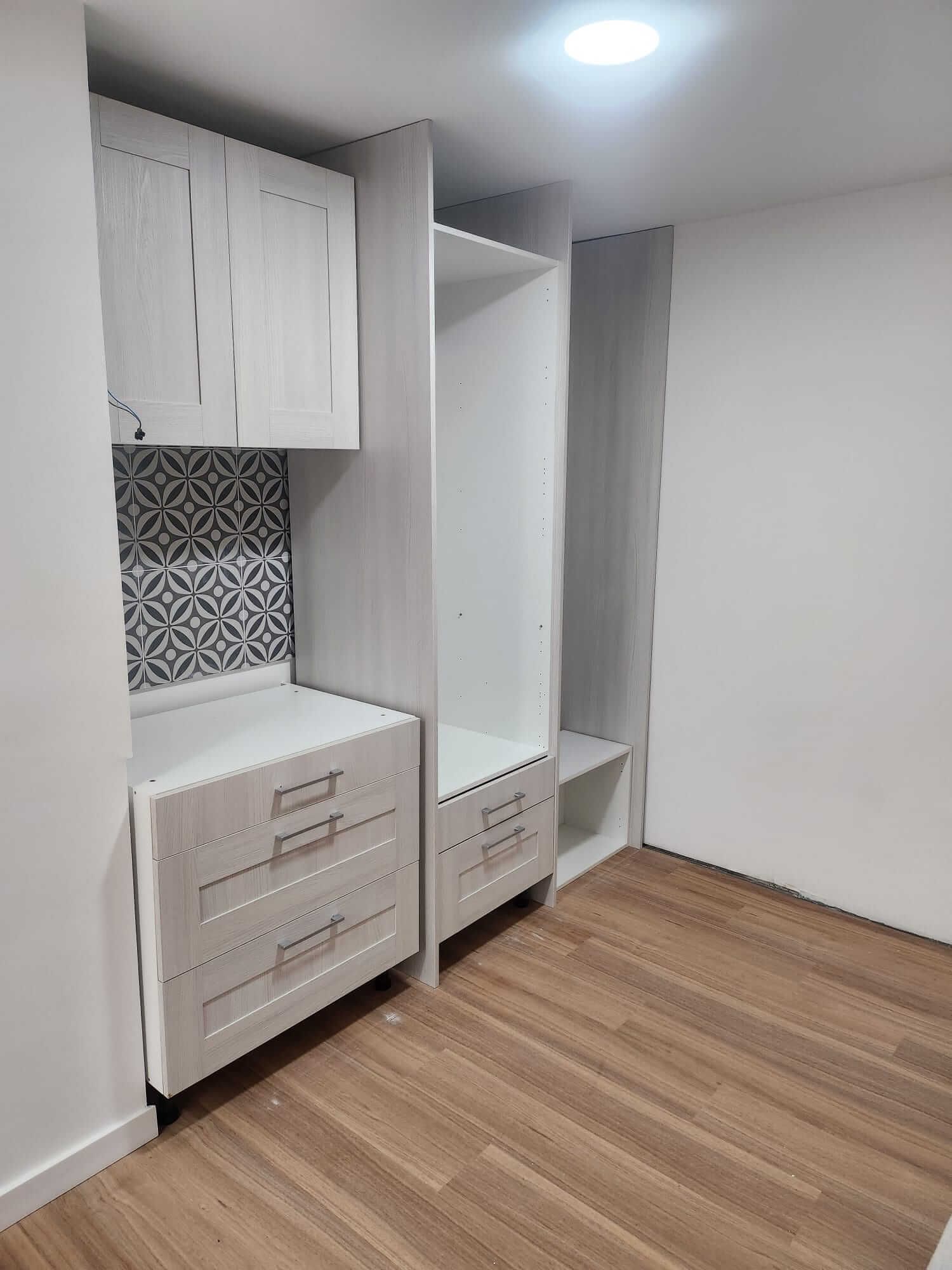 Gabinetes y cajones de madera clara con protector contra salpicaduras de azulejos con estampado azul y blanco.