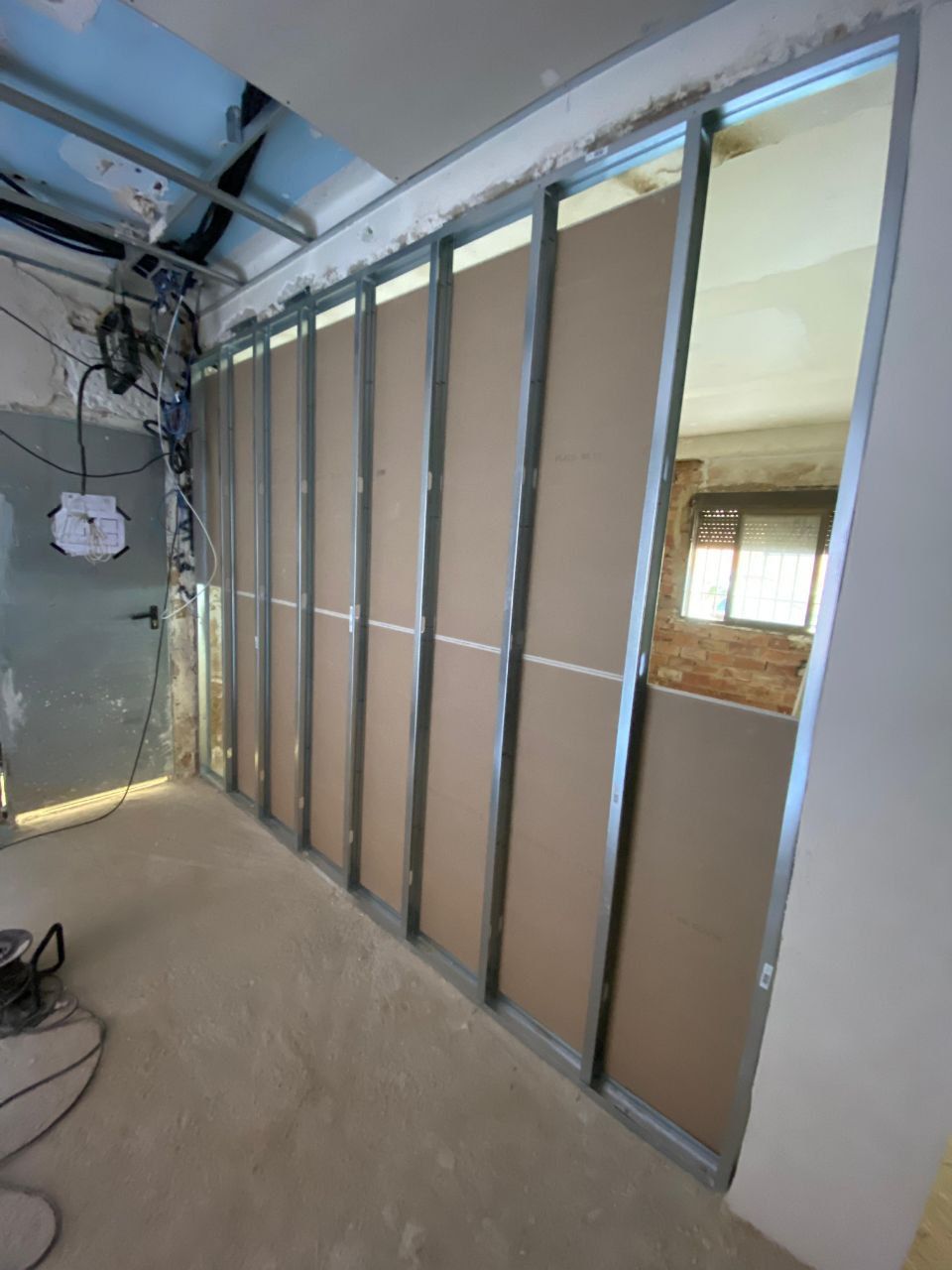 Vista interior de una habitación en construcción. Paneles de yeso instalados sobre una estructura metálica.