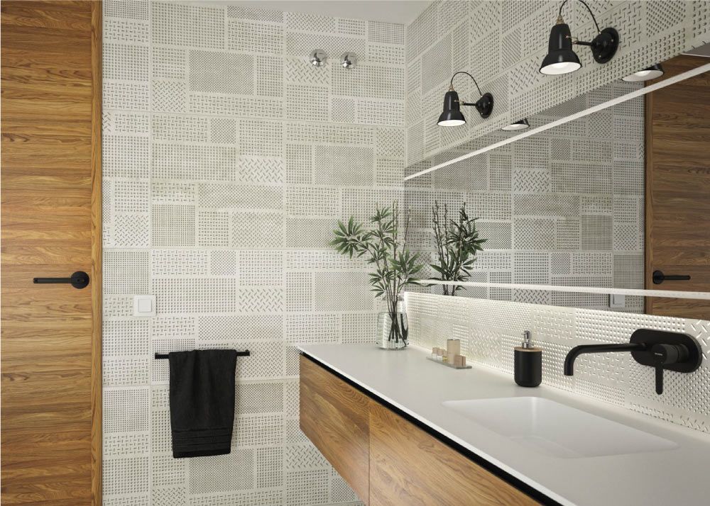 Baño con puerta de madera, encimera blanca y pared de azulejos beige estampados; accesorios negros.