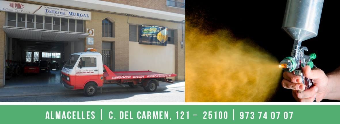 Camión rojo estacionado frente a un garaje; una boquilla de pulverización naranja rocía líquido sobre una superficie blanca.