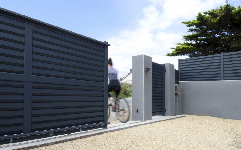 Portail coulissant entreouvert avec une famme à vélo qui sort