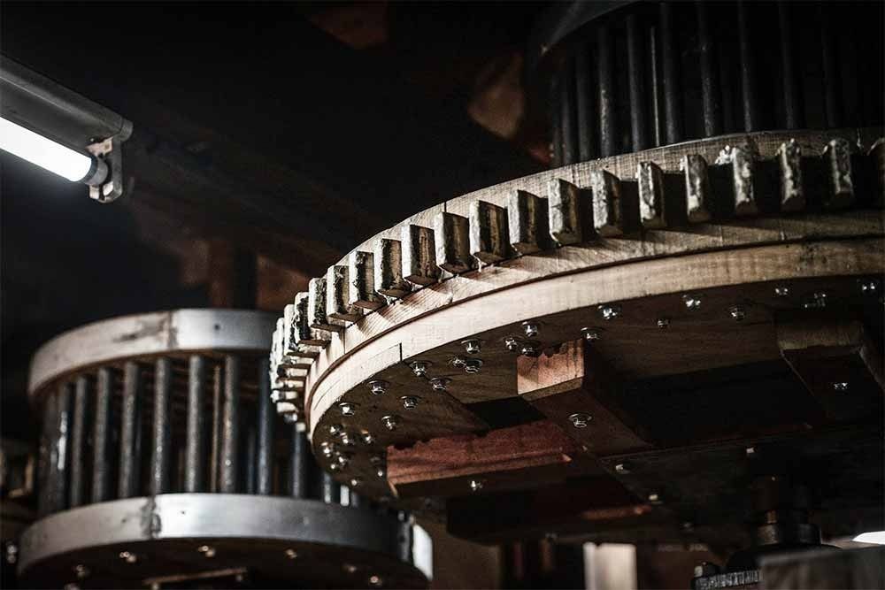 Primer plano de engranajes de madera, entorno industrial, que muestra el funcionamiento interno de la maquinaria.